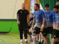 Maciej Reichel, trener, obserwuje mecz piłki ręcznej. Zawodnicy w niebieskich koszulkach czekają na swoją kolej.