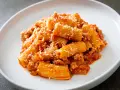 Un piatto invitante di pasta alla zozzona, con rigatoni conditi con un ricco ragù e abbondante parmigiano grattugiato.