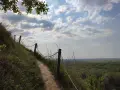 Ścieżka na zboczu Góry Pieprzowe. W oddali rozciąga się zielona dolina.