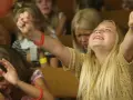 Junge Mädchen erleben emotionale Momente bei einer evangelistischen Religionsveranstaltung, eine jubelt, die andere weint.