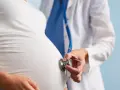 Lekarz osłuchuje brzuch ciężarnej kobiety stetoskopem. Dbałość o zdrowie w ciąży to podstawa.