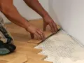 Manos colocando tablones de madera para un piso de parquet. Calculando el precio parquet piso 70m2.