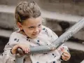 Mała dziewczynka z spiętymi włosami i spinką, w bluzie w kwiatki, opiera się o poręcz. Jej spojrzenie sugeruje dziwne zachowanie 2,5 latka.
