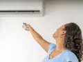 Donna con telecomando regola il condizionatore, la canalina condizionatore design si integra perfettamente.