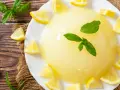 Delizioso gelo di limone su piatto bianco, decorato con spicchi di limone fresco e foglie di menta.