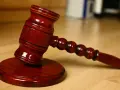 Młotek sędziowski na drewnianym stole. Symbolizuje sprzedaż mieszkania z wpisem komorniczym i decyzje prawne.