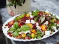 En färgglad sallad med granatäpple, tomater, fetaost och basilika, perfekt som sallad till grillat.