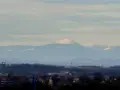 Widok na Śnieżkę i Karkonosze z Wrocławia. Widać ośnieżone szczyty górskie na tle błękitnego nieba.