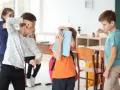 Chłopcy w klasie doświadczają konfliktów między rówieśnikami. Jeden chłopiec grozi pięścią, inny zasłania się książką.