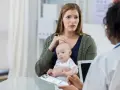 Zaniepokojona mama z niemowlęciem na rękach rozmawia z lekarzem. Zastanawia się nad chwilowym zawieszaniem się dziecka.