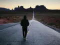 Człowiek idzie pustą drogą w Monument Valley, pogrążony w mysleniu tunelowym, z widokiem na skalne formacje w oddali.