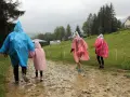 Deszcz w Zakopanem? Nic nie szkodzi! Rodzina w kolorowych pelerynach idzie ścieżką do kasy biletowej, ciesząc się widokami.