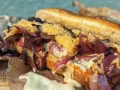 Ein saftiger Philly Cheesesteak-Sandwich mit geschmolzenem Käse, karamellisierten roten Zwiebeln und zartem Rindfleisch auf einem Baguette.