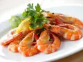 Gambas al ajillo receta: jugosas gambas cocinadas con ajo y perejil, servidas con limón y lechuga en un plato blanco.