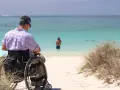 Mężczyzna na wózku inwalidzkim podziwia morze. Paraplegia co to? To utrata czucia i ruchu w nogach, ale nie ogranicza to radości życia.