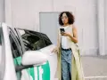 Frau mit Handy am Auto, bereit, einen Bolt anzurufen.