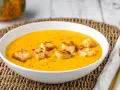 Una cremosa vellutata di zucca, guarnita con crostini dorati, pronta per essere gustata in una fredda giornata autunnale.