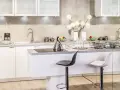 Nowoczesna kuchnia w stylu glamour: inspiracje dla eleganckiego wnętrza. Białe meble, chromowane dodatki i subtelne dekoracje tworzą luksusową atmosferę.