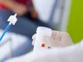 Ręka w rękawiczce trzyma pojemnik z płynem do cytologii. Obok leży specjalna szczoteczka do pobierania wymazu.
