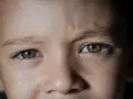 Dziecko o niezwykłych, zielono-brązowych **kolorach oczu**, w których odbija się światło.