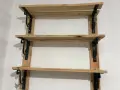 Scaffali fai da te garage: tre ripiani in legno grezzo, fissati a parete con staffe nere decorative. Perfetti per organizzare attrezzi e materiali.