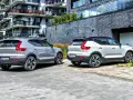 Dwa modele Volvo XC40, jeden srebrny, drugi biały, zaparkowane przed nowoczesnym budynkiem.