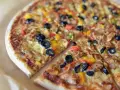 Pyszna pizza z kurczakiem, oliwkami i kolorową papryką. Wiele rodzajów pizzy może się równać z jej smakiem.