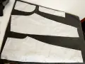 Wykroje papierowe do spodni (przód i tył) przypięte do ciemnego materiału. Rozpoczynamy proces, jak zrobić wykrój spodni.