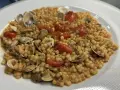 Un piatto invitante di fregola con vongole, pomodorini e prezzemolo, pronto per essere gustato.