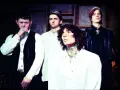 Les membres de Bring Me The Horizon posent ensemble, vêtus de blanc et de noir, dans une ambiance sombre et stylisée.