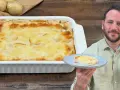 Un uomo sorride mostrando una fetta di parmigiana di patate appena sfornata, dorata e filante.