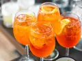 Cztery orzeźwiające drinki Aperol Spritz z lodem i plasterkami pomarańczy. Idealny aperol przepis na letnie popołudnie.