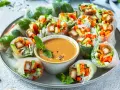 Frische Sommerrollen gefüllt mit Gemüse und Tofu, serviert mit cremiger Erdnusssauce. Ein leichter Genuss für warme Tage.