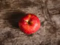Czerwone jabłko z kroplami wody na drewnianym tle.