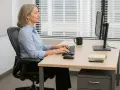 Kvinna arbetar vid datorn i en ergonomisk kontorsmiljö.
