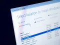 Instalator Windows 11 pokazuje opcje zarządzania partycjami. Kursor myszy wskazuje opcję "Usuń partycję", przygotowując do formatowania dysku.