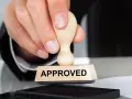 Dłoń z pieczątką "APPROVED" nad poduszką z tuszem. To symbol zatwierdzenia, jak certyfikat AEO.