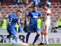 Piłkarze Karlsruher SC w niebieskich strojach, jeden z nich z numerem 3, otoczeni dymem z rac.