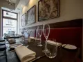 Elegancko nakryte stoły w restauracji z gwiazdką Michelin w Polsce. Czerwone obicia, obrazy na ścianach i kieliszki zapraszają na wyjątkowe doznania kulinarne.