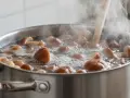 Grzyby gotujące się w garnku na kuchence, unosząca się para wodna.