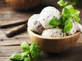 Schüssel mit Stracciatella Eis und frischer Minze auf Holzhintergrund.