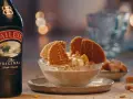 Baileys Eis Rezept: Cremiges Eis mit Karamell und Waffeln, daneben eine Flasche Baileys.