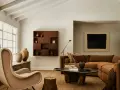 Un acogedor salón con chimenea de piedra, sillón de tela, sofá marrón y mesa de centro de madera. El arte de pared y las cerámicas añaden un toque de estilo chino hogar.