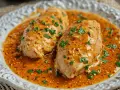 Dos pechugas de pollo en una sabrosa salsa naranja, espolvoreadas con perejil fresco picado.