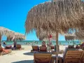 Słoneczny dzień na plaży w Rumunii nad Morzem Czarnym. Leżaki i parasole z trawy zapraszają do odpoczynku.