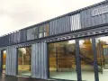 Nowoczesne centrum lokalne Kamionek, zbudowane z kontenerów. Ten innowacyjny kamionkowy materiał budowlany tworzy przestrzeń z przeszklonymi fasadami i balkonem.