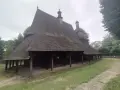 Drewniany kościół w Sękowej z charakterystycznym, wielospadowym dachem krytym gontem, otoczony zielenią.