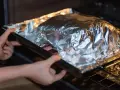 Mains dans un plat recouvert d'aluminium au four, prêt à cuire.