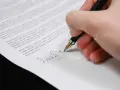Dłoń podpisuje dokument, być może oświadczenie o odrzucenie spadku.