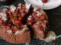 Ein saftiger schoko kirsch kuchen, bestäubt mit Puderzucker, wird auf einem Gitter präsentiert. Eine Gabel hebt ein Stück ab.